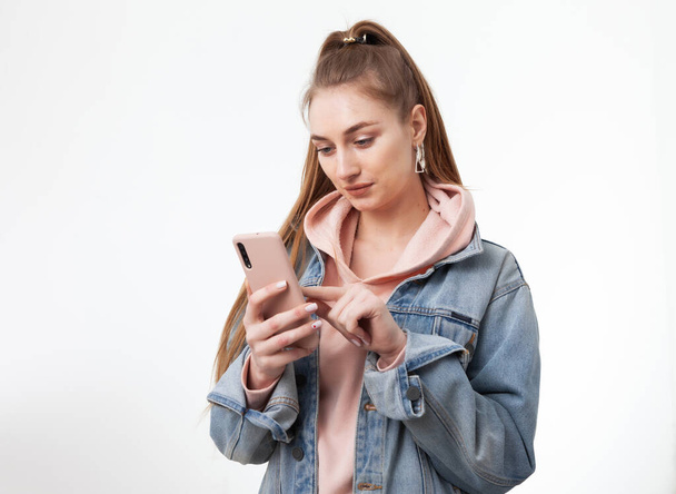 Νεαρή ελκυστική καυκάσια γυναίκα που χρησιμοποιεί smartphone απομονωμένο σε λευκό φόντο - Φωτογραφία, εικόνα