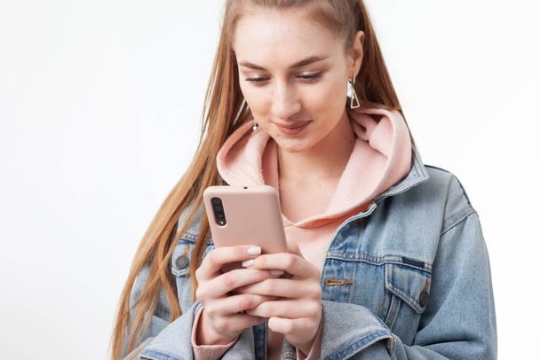 Mladý atraktivní běloška žena pomocí smartphone izolované na bílém pozadí - Fotografie, Obrázek