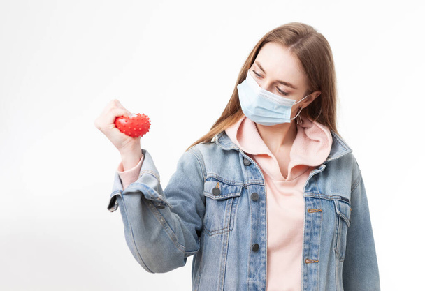 Femme sérieuse dans le masque médical serre souche de virus sur fond blanc - Photo, image
