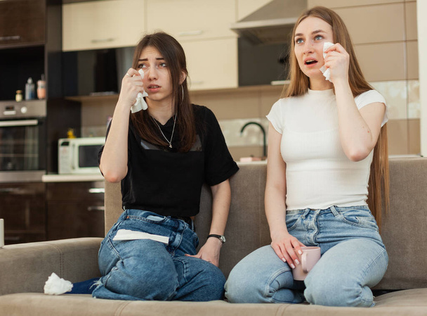 Zwei emotionale Freundinnen sehen ein Melodram im Fernsehen und weinen auf dem Sofa - Foto, Bild