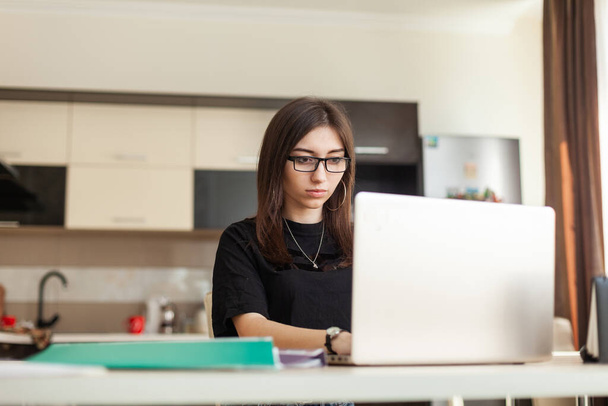 Távolsági tanulás vagy online munka koncepció. A nő laptopot használ, miközben a nappaliban ül egy asztalnál. Munkaterület - Fotó, kép