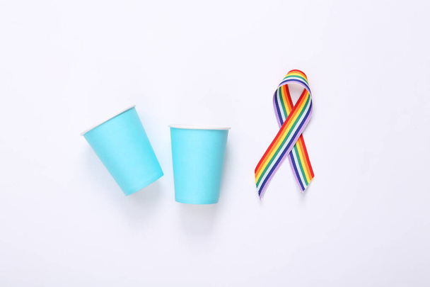 Copas de papel con lazo de arco iris LGBT símbolo de cinta de orgullo sobre fondo blanco. Vista superior - Foto, Imagen
