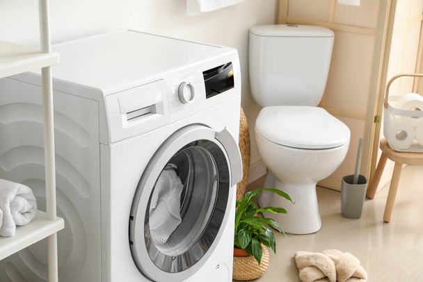 Modern washing machine with laundry in bathroom - Foto, imagen