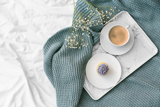 Bandeja con taza de café, magdalena y flores en la cama - Foto, imagen