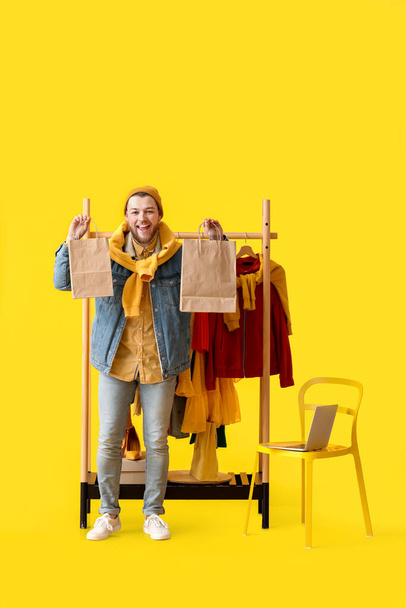 Male stylist with shopping bags on color background - Foto, Imagem