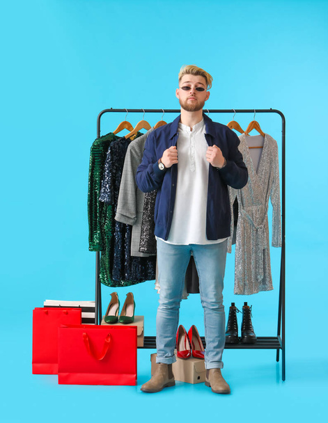 Male stylist near rack with clothes on color background - Foto, Imagen