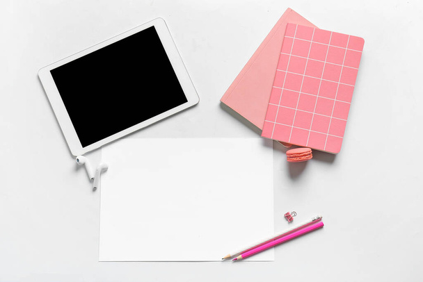 Composición con hoja en blanco de papel, tableta, auriculares y papelería sobre fondo blanco - Foto, imagen
