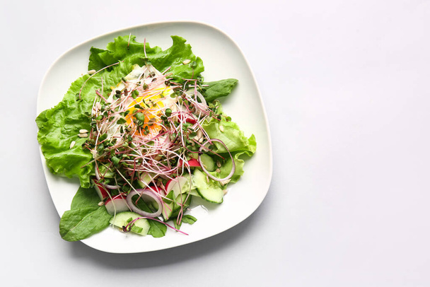 Tányér ízletes saláta zöldségekkel, tükörtojás és mikrozöld világos alapon - Fotó, kép