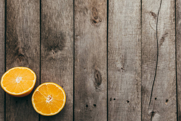 Sliced halves of orange fruit on gray wooden background. Pulp. High quality photo - Foto, Imagem