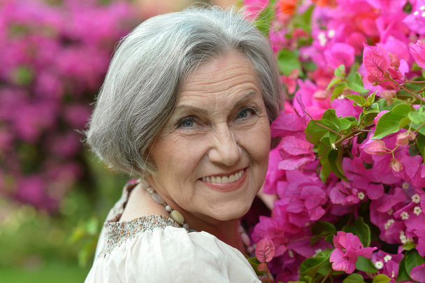 Older woman on walk with pink flowers - Fotoğraf, Görsel
