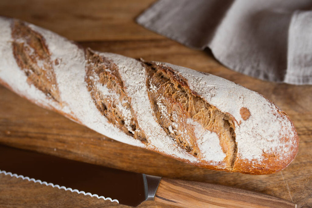 Fresh crispy homemade baguette on wooden cutting board. Close-up with short depth of field. - Photo, image