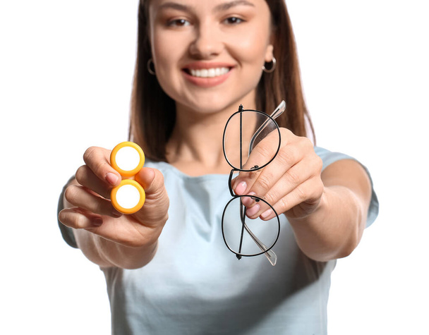Mujer joven con lentes de contacto y anteojos sobre fondo blanco, primer plano - Foto, imagen