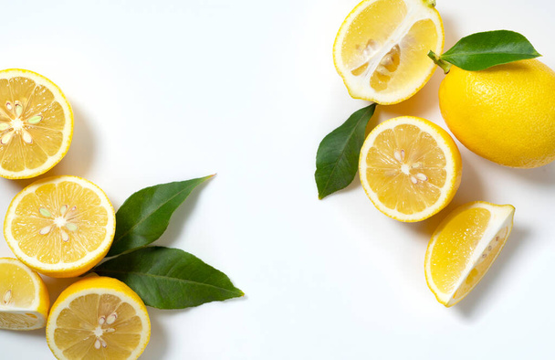Lemons placed on a white background with copy space and cut in half. View from directly above - Foto, Bild