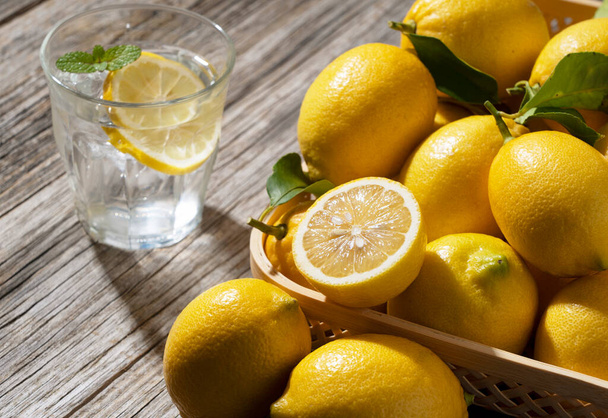 A lot of lemons and lemon water in a basket on a wooden background - Φωτογραφία, εικόνα