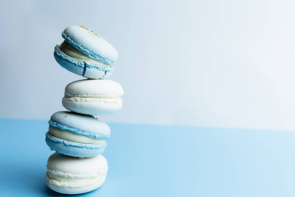 Valkoinen ja sininen macaronit pöydällä, macaronit valkoisella sinisellä taustalla. Laadukas kuva - Valokuva, kuva