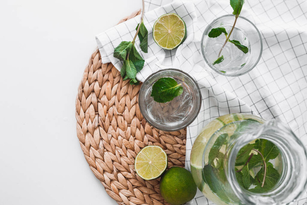 Detox water with lime fruit and mint leaves in jar and glasses. - Photo, Image