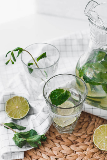 Detox water with lime fruit and mint leaves in jar and glasses. - Foto, Imagem