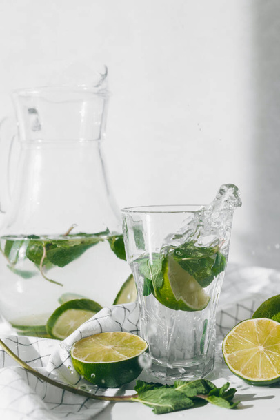 Детоксикационная вода с лаймовыми фруктами и мятными листьями. Свежий мятный лимонад. - Фото, изображение