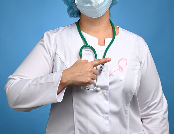 medic woman in white coat, pink ribbon pinned to the robe, symbol of the fight against breast cancer in October , close up - Fotografie, Obrázek