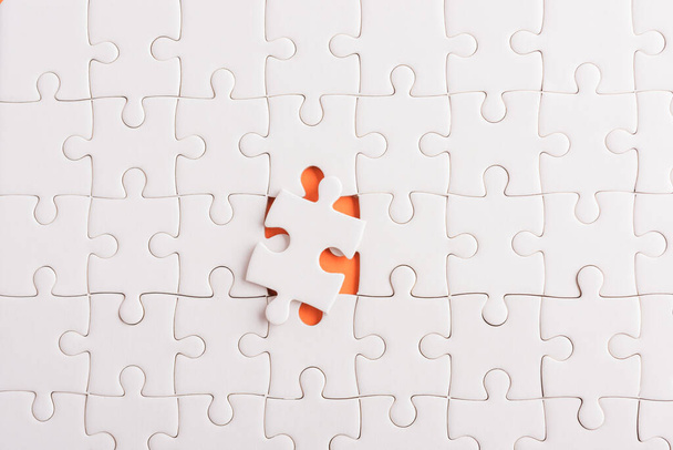 Top view flat lay of paper plain white jigsaw puzzle game texture incomplete or missing piece, studio shot on an orange background, quiz calculation concept - Fotografie, Obrázek