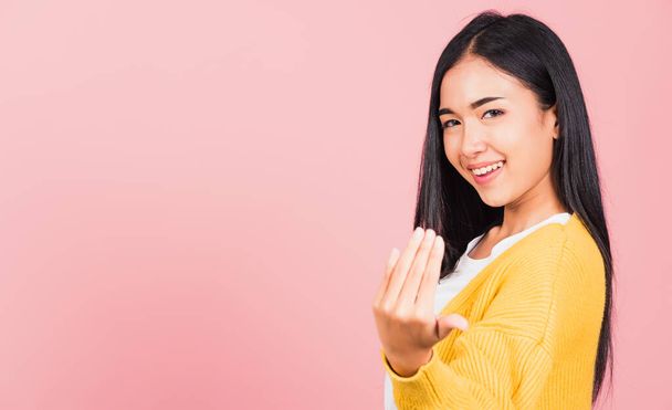 Happy Asian portrait beautiful cute young woman teen smile positive friendly making gesture hand inviting to come here with hand look to camera studio shot isolated on pink background with copy space - Фото, зображення