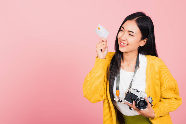 Happy Asian portrait beautiful young woman excited smiling photographer holding credit credit card bank and retro vintage photo camera ready travel isolated on pink background, tourism and vacation - Photo, Image