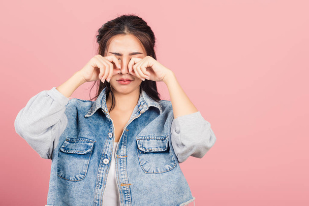 Asian portrait beautiful cute young woman wear denim bad mood her cry wipe tears with fingers, studio shot isolated on pink background, Thai female feeling sad unhappy crying with copy space - Фото, изображение