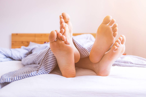 Close up a couples uncovered feet sleeping in bed, morning - 写真・画像