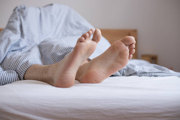 Close up uncovered female adult feet sleeping in bed, morning - Φωτογραφία, εικόνα