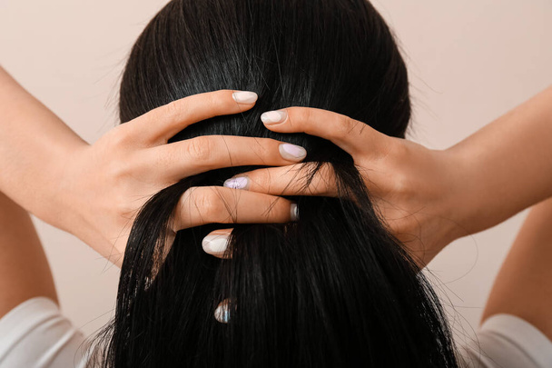 Young woman with beautiful manicure touching her hair on color background - Photo, image