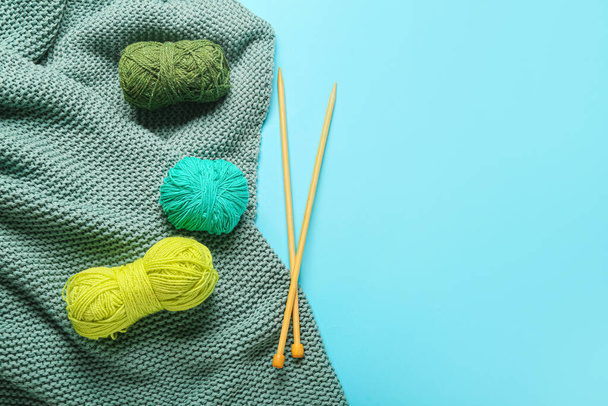Yarn with knitting needles and plaid on color background - Fotó, kép