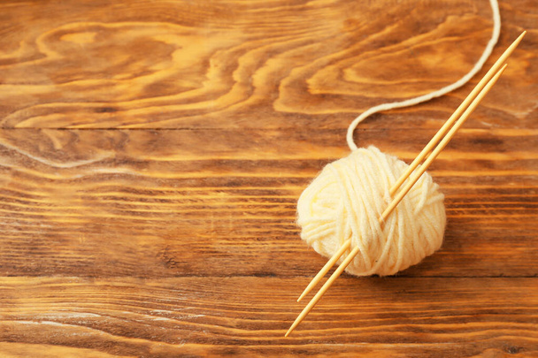 Yarn and knitting needles on wooden background - Foto, afbeelding