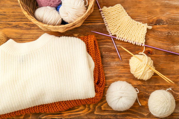 Yarn, knitting needles and sweater on wooden background - Photo, Image