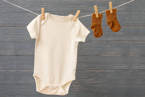 赤ちゃんの服は暗い木製の背景にロープにかかって - 写真・画像