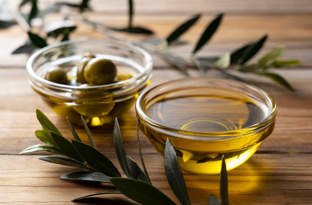 olive oil and olives on wooden background - Foto, afbeelding