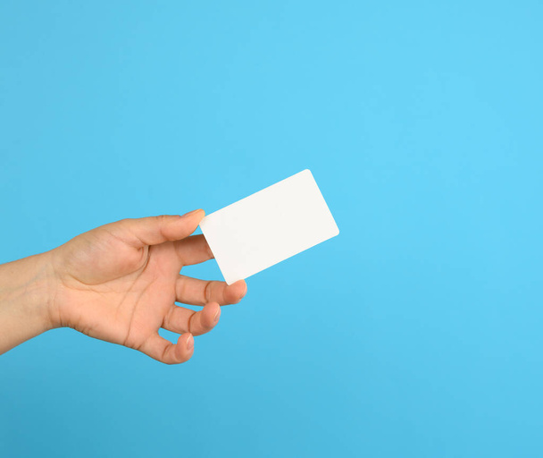 female hand holding a white black business card, blue background - Photo, Image