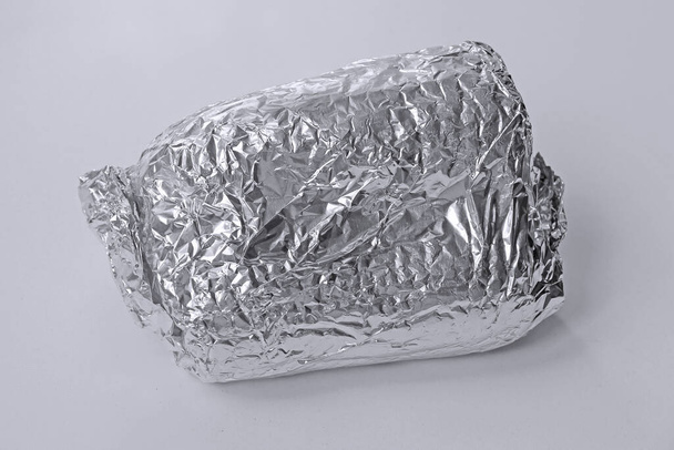 Sandwich wrapped up in silver aluminum foil isolated on white background - Photo, image