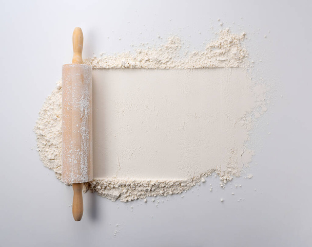 A rolling pin rolled over flour on a white background. View from directly above. - Фото, изображение