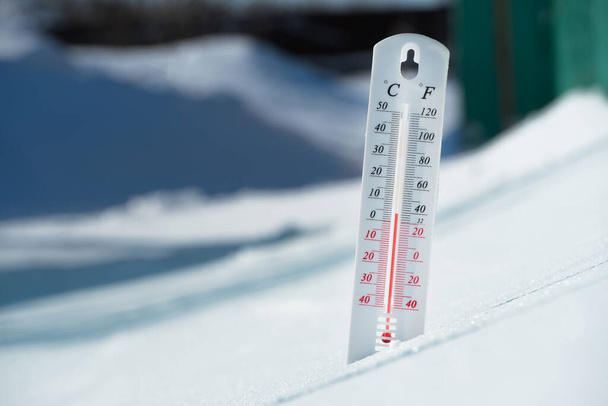 In winter or spring the thermometer lies on the snow and shows a negative temperature in cold weather.Meteorological conditions with low air and ambient temperatures.Climate change and global warming - Φωτογραφία, εικόνα