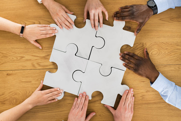 Teamwork Meeting Hands Solving Jigsaw Puzzle. Overhead View - Photo, image