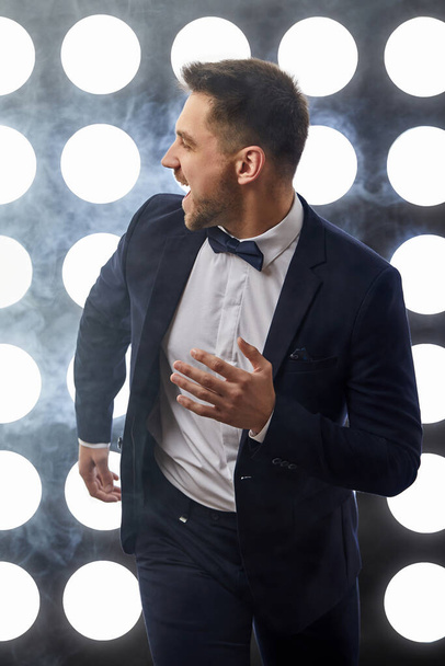 handsome man in tuxedo run against the backdrop of spotlights and smoke. night life - Foto, immagini