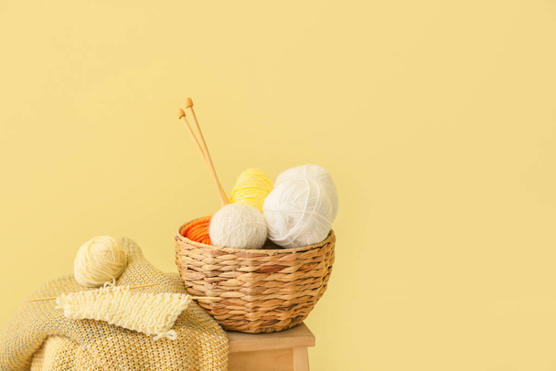 Panier avec fil à tricoter, aiguilles et plaid sur échelle sur fond de couleur - Photo, image