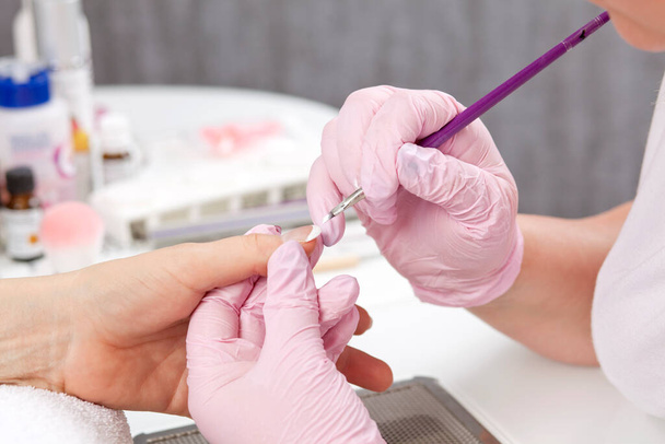 closeup of female hand getting nail manicure by professional manicurist - Photo, image