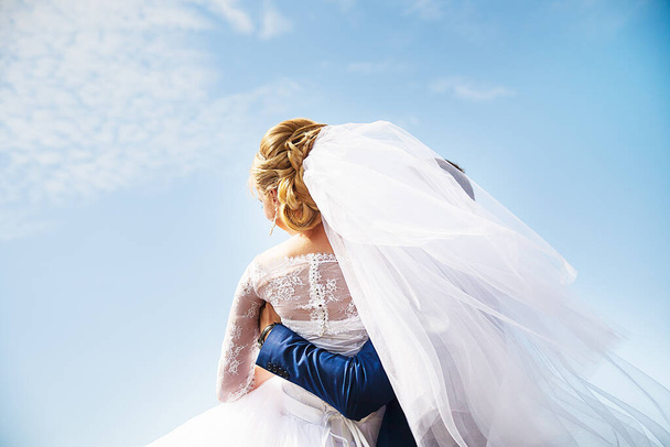 Groom holding his bride with a bouquet in hands - Foto, Bild
