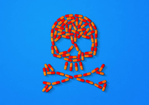 Skull made of orange capsule pills isolated on blue background. 3D illustration - Valokuva, kuva