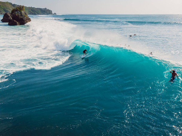 August  8, 2021. Bali, Indonesia. Aerial view with surfing on big barrel wave. Blue perfect waves and surfers in ocean at Padang Padang - Foto, Imagem
