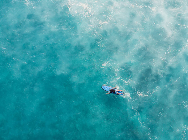 Widok z lotu ptaka na longboard w błękitnym oceanie z pianką za falą. Widok z góry - Zdjęcie, obraz