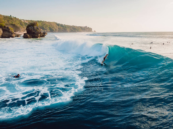 August  8, 2021. Bali, Indonesia. Aerial view with surfing on big barrel wave. Blue perfect waves and surfers in ocean at Padang Padang - Photo, Image