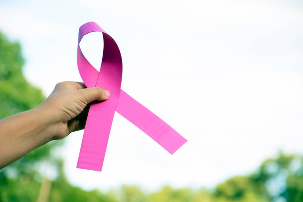 Ruban de papier rose tenant dans les mains de waman, concept de soutien pour lutter contre le cancer du sein de waman qui est malade de canner à travers le monde, foyer doux et sélectif. - Photo, image