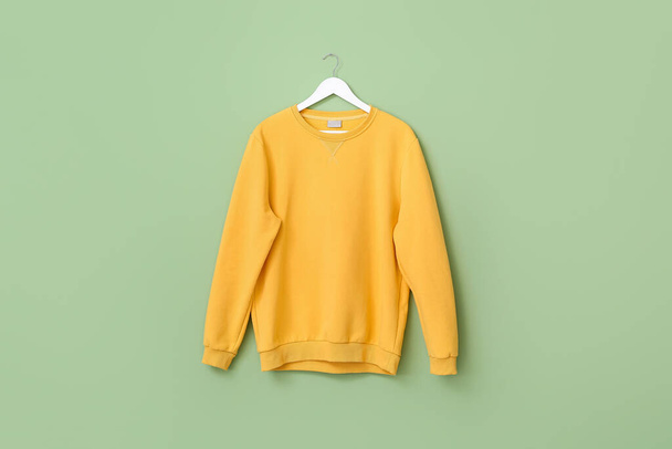 Percha con suéter elegante sobre fondo de color - Foto, Imagen